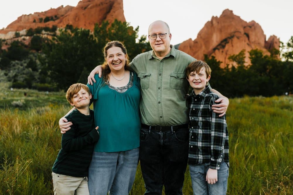 Family portrait outdoors at red rock landscape, diverse family enjoying nature, happy parents with children in scenic Colorado setting, summer day.